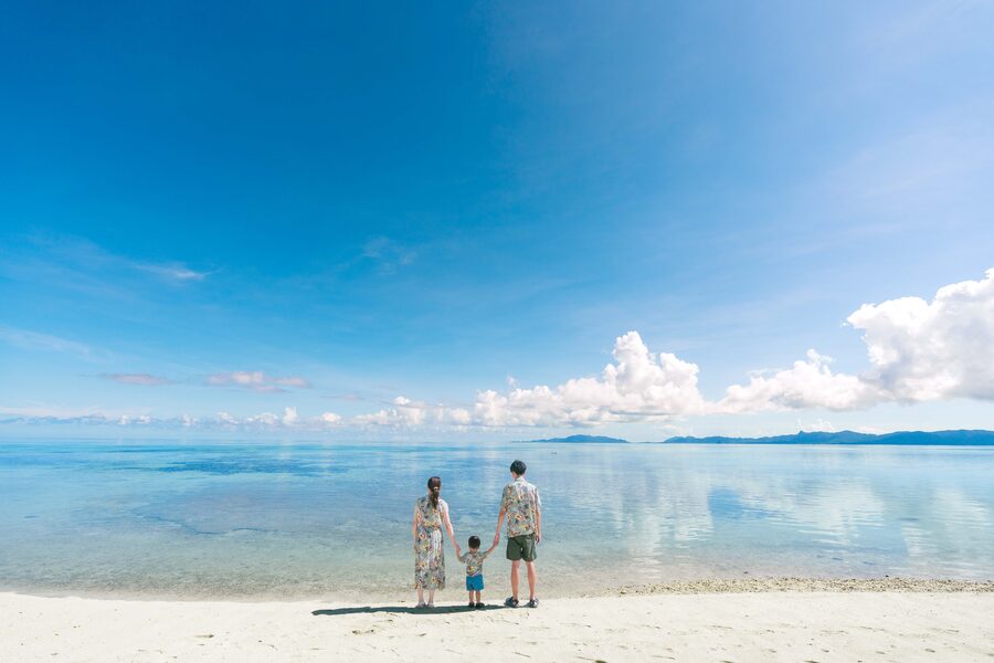 べた凪が撮影した石垣島の白い砂浜と遠浅の海に立つ家族
